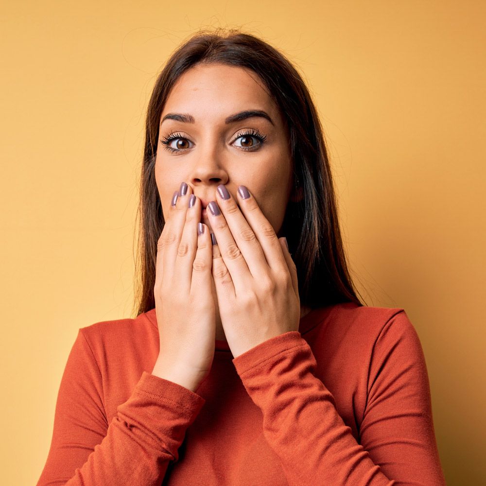 Woman hiding mouth behind hands